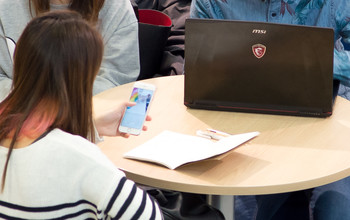 Students using a laptop and a smart phone at a table